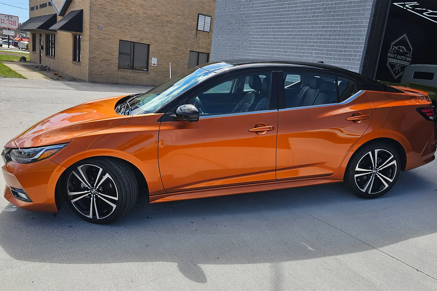 A orange car parked in front of a building.