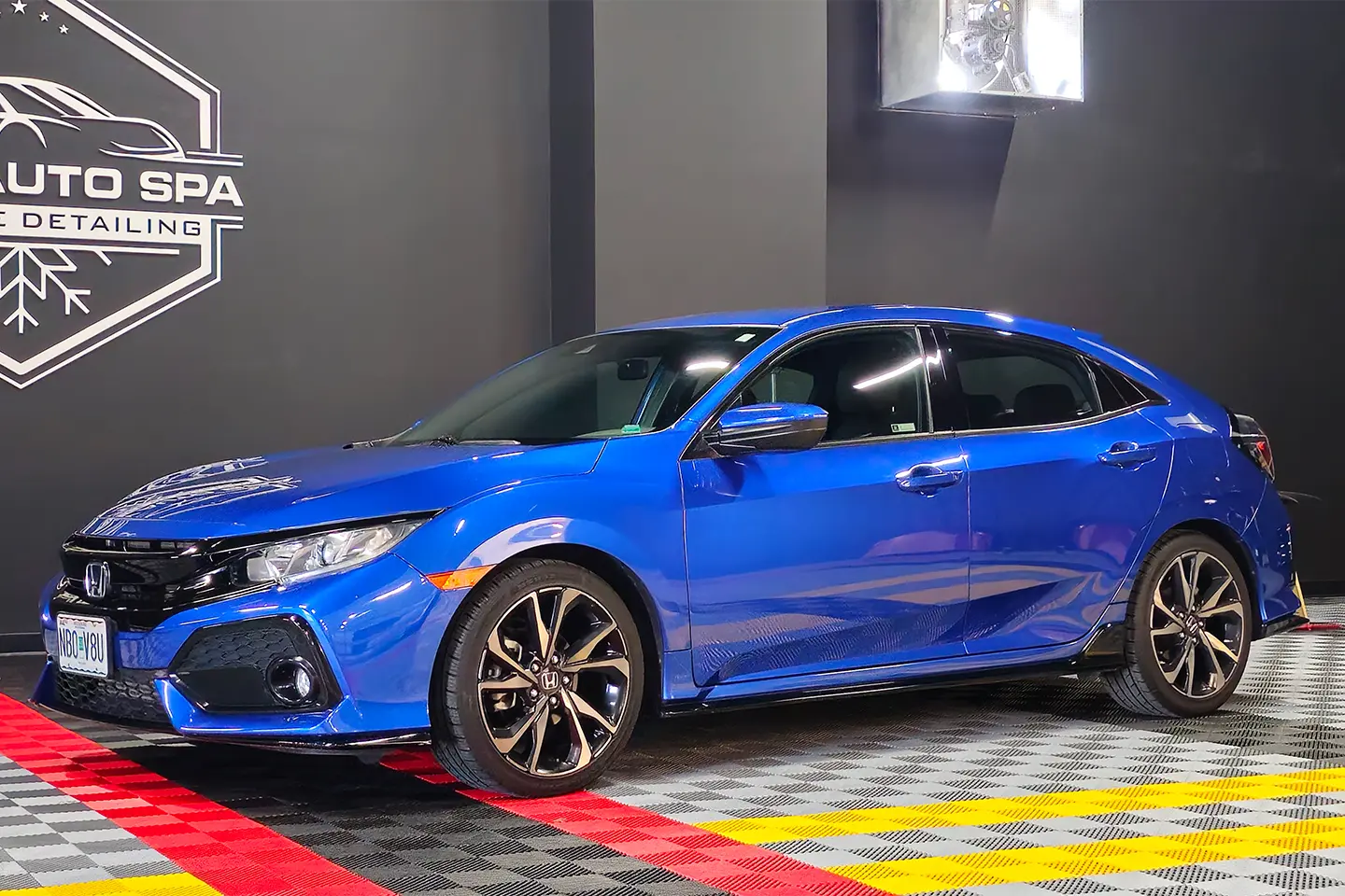 A blue car parked in front of a wall.